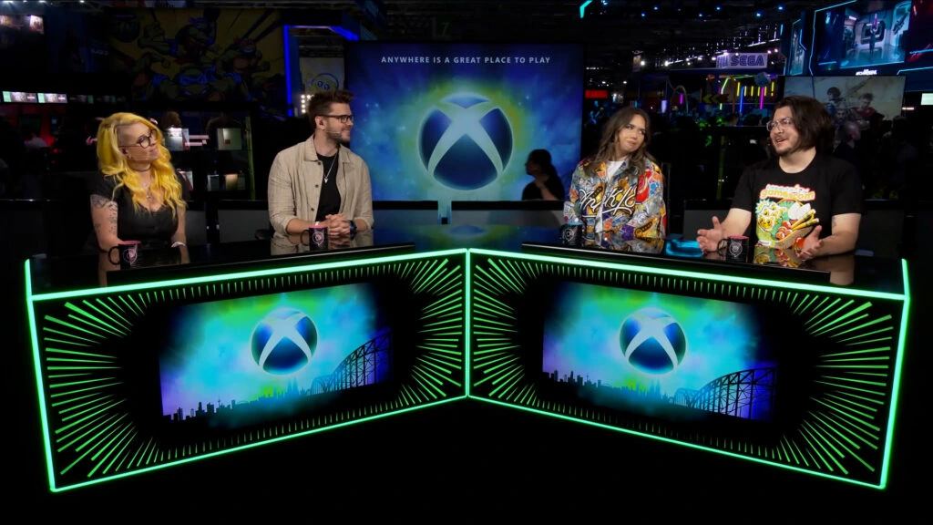 Xbox broadcast desk at a gamescom event with gaming screens and green lighting