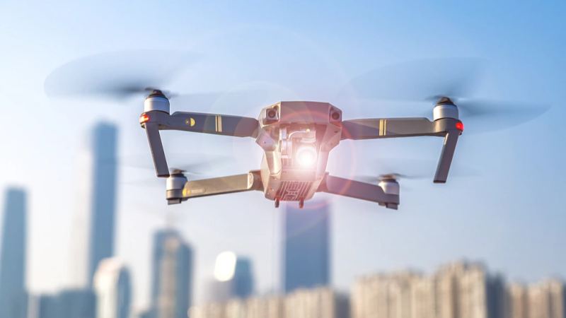 Split image showing an industrial robot arm on the left, a humanoid robot running on the center, and a military drone silhouette over a city skyline on the right.