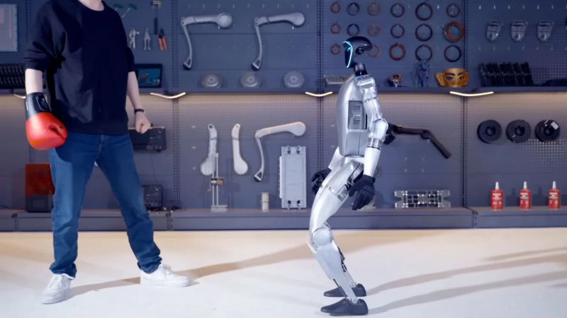 Unitree bipedal humanoid robot dynamically engaging in autonomous physical sparring tests inside a robotics development laboratory.