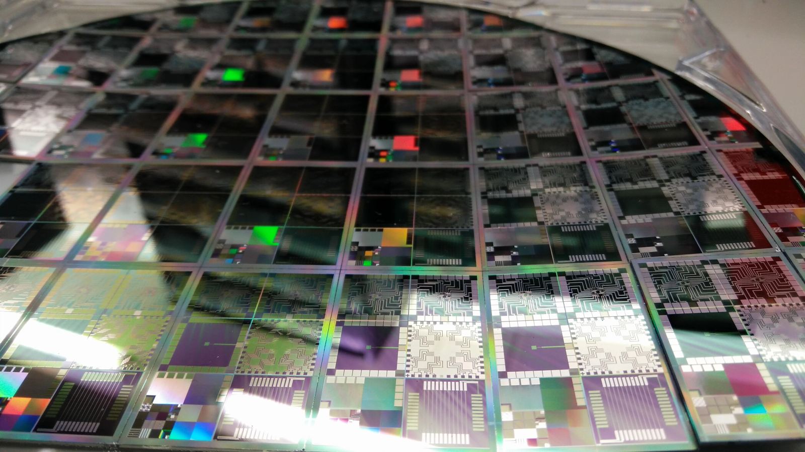 Silicon semiconductor wafer containing hundreds of integrated circuits during cleanroom fab manufacturing.