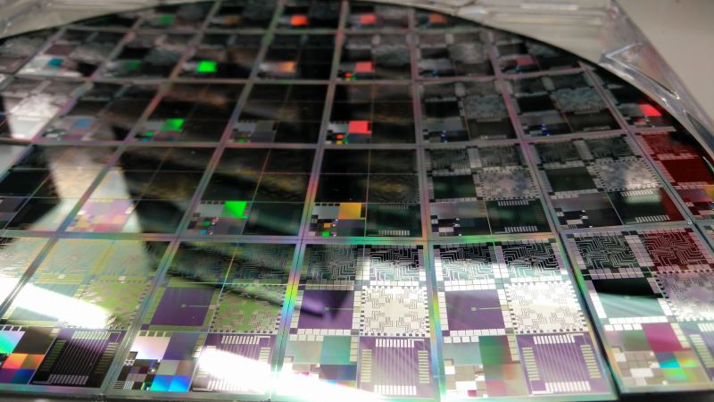 Silicon semiconductor wafer containing hundreds of integrated circuits during cleanroom fab manufacturing.