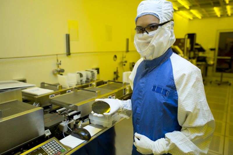 Cleanroom technician inspecting advanced silicon wafer containing high-density machine learning accelerator chiplets