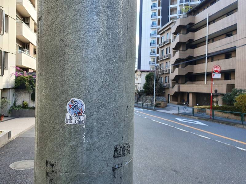 Pegatina de la comunidad Dogecoin en Tokio que representa la expansión del ecosistema de moneda digital