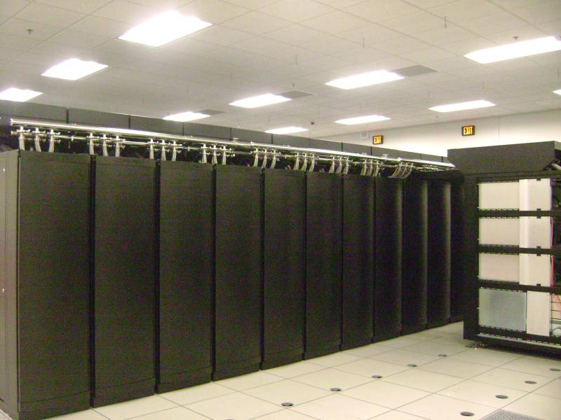 Supercomputer-Hardwareschränke, die die hochdichte verteilte Computerinfrastruktur veranschaulichen, die für das Training skalierbarer KI-Modelle erforderlich ist