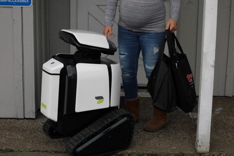 Autonomous electric sidewalk delivery robot navigating pedestrian pathways for contactless retail fulfillment.