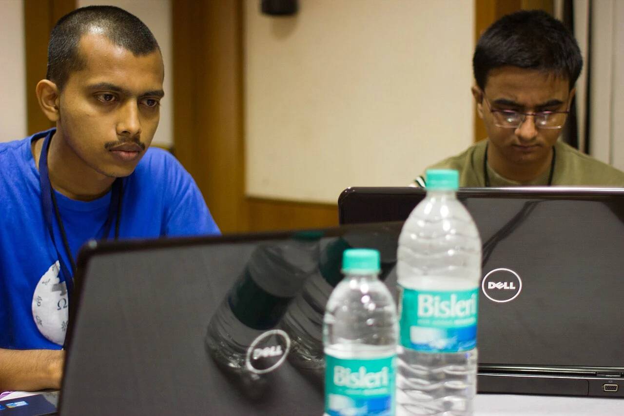 Software engineers collaborating on development workstations, compiling container runtimes and microservices code.